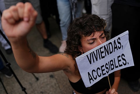An activist holds a banner reading in Spanish "Affordable housing" during a protest near the Spanish Parliament following the eviction of 87-year-old Maria del Carmen Abascal to demand stronger laws to protect renters in Madrid, Spain, Friday, Oct. 2, 2026. 
