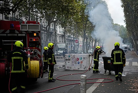 Firefighters extinguish a fire as students protest against under-resourced schools in Lyon, France, Friday, Oct. 2, 2026. 
