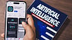 Column | The Last Face In The Queue Pexels/ Sanket Mishra : A smartphone displaying AI app with a book on AI technology in the background