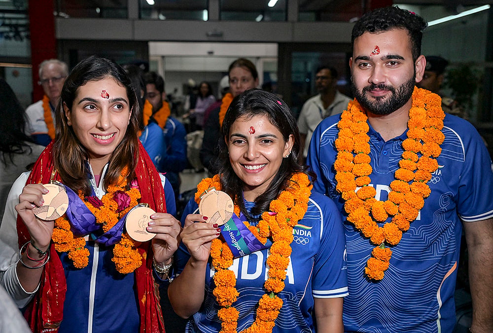 Indian shooters Parinaaz Dhaliwal, left, Maheshwari Chauhan, centre, and Anish pose for a photo at Indira Gandhi International Airport upon their return from the Asian Games in Japan, in New Delhi. - | Photo: PTI