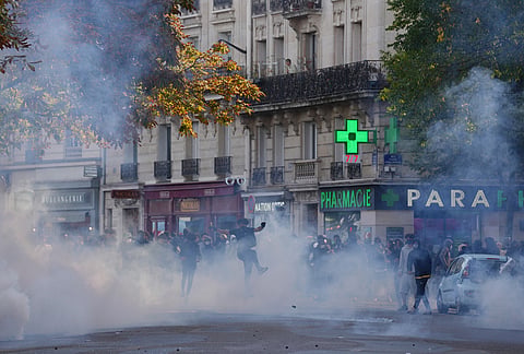 A student kicks a tea gas canister during a protest against under-resourced schools, in Paris, Friday, Oct. 2, 2026. 
