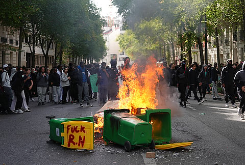 Students burn garbage bins as they protest against under-resourced schools, in Paris, Friday, Oct. 2, 2026. 
