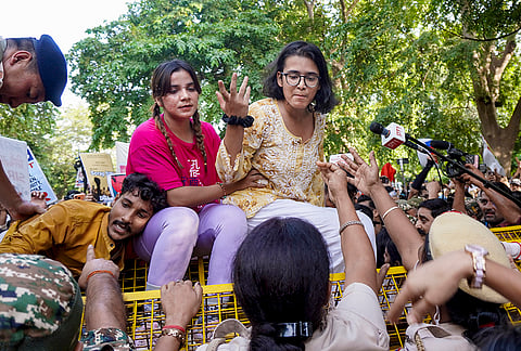 All India Students' Association (AISA) national president Neha Bora climbs a police barricade near Ashoka Road during a protest demanding the removal of Chief Election Commissioner (CEC) Gyanesh Kumar, in New Delhi.