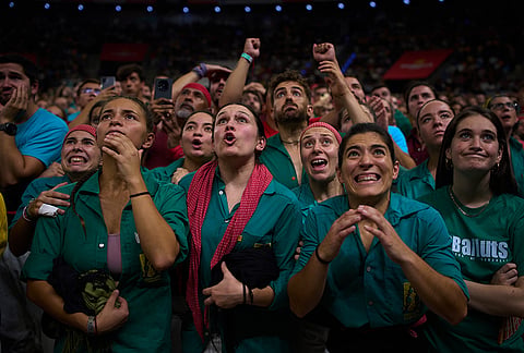 Members of Castellers de Sabadell react as another team forms a "castell" human tower during the 30th Concurs de Castells, or Human Tower Competition, in Tarragona, Spain, Saturday, Oct. 5, 2026. 
