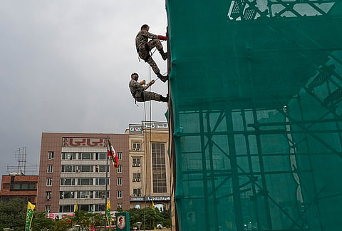 Iranian army members rappel down a wall during the opening ceremony of one of the military training centers for volunteers being set up throughout squares in downtown Tehran, Iran, Saturday, Oct. 3, 2026. 