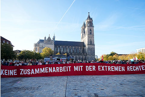 People attend a protest against the far-right AfD, Alternative for Germany, party Prior to the constituent session of the new elected German federal state parliament of Saxony-Anhalt in Magdeburg, Germany, Tuesday, Oct. 6, 2026. Poster reads: No cooperation with the far right. 
