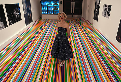 A model poses at the entrance of "The 90s: Art and Fashion exhibition" during a media preview at Tate Britain in London, Tuesday, Oct. 6, 2026. 
