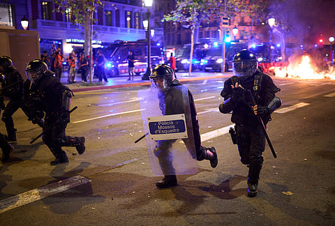 Riot police officers run after protesters during clashes following a demonstration over Spain's housing crisis, hours after Prime Minister Pedro Sánchez announced an early general election, in Barcelona, Spain, Monday, Oct. 5, 2026. 

