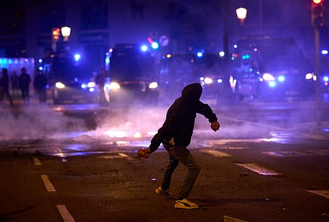 A protester throws stones at the police during clashes following a demonstration over Spain's housing crisis, hours after Prime Minister Pedro Sánchez announced an early general election, in Barcelona, Spain, Monday, Oct. 5, 2026. 

