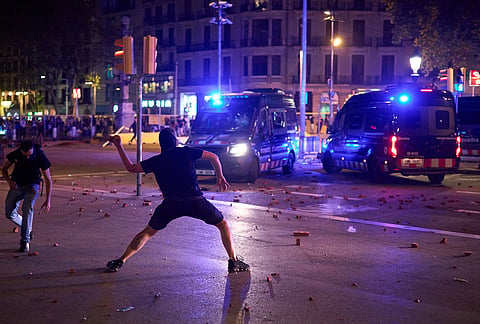 A protester throws stones at the police during clashes following a demonstration over Spain's housing crisis, hours after Prime Minister Pedro Sánchez announced an early general election, in Barcelona, Spain, Monday, Oct. 5, 2026. 

