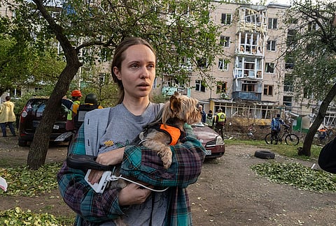 A woman holds her dog in the yard of a residential house damaged by a Russian strike on Kharkiv, Ukraine, Monday, Oct. 5, 2026. 
