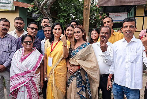 Congress candidate for the Nagaon Lok Sabha by-election, Sibamoni Bora, yellow saree, displays her indelible ink-marked finger alongside supporters after casting her vote at a polling station, in Nagaon district, Assam.