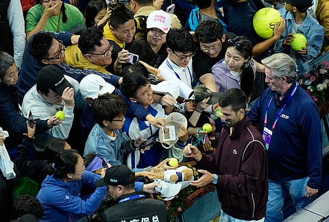 Novak Djokovic, of Serbia, signs autographs for fans after winning the men's singles final match against Alex De Minaur, of Australia at the China Open tennis tournament in Beijing, Tuesday, Oct. 6, 2026. 