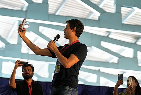 Indian influencer and activist Dhruv Rathee, center, and Abhijeet Dipke, founder of Cockroach Janta Party, left, take selfies with others during a protest gathering demanding the resignation of the country's election chief Gyanesh Kumar, in Bengaluru, India, Thursday, Oct. 8, 2026. 