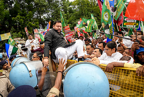 Bihar Leader of Opposition and RJD leader Tejashwi Yadav climbs over police barricades as police personnel attempt to stop him during the INDIA bloc's march to Lok Bhavan, in Patna. Opposition leaders and workers from RJD, Congress, and Left parties staged the demonstration against alleged irregularities in the Special Intensive Revision (SIR) of electoral rolls. 
