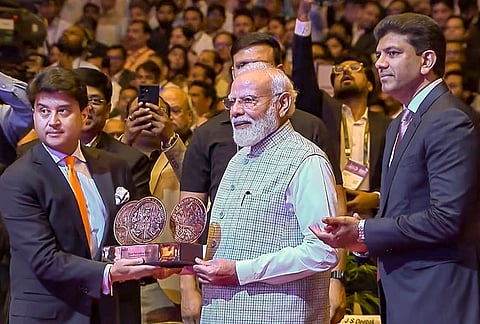 Prime Minister Narendra Modi is presented with a memento by Union Minister for Communications Jyotiraditya Scindia, left, during the inauguration of the 10th edition of India Mobile Congress (IMC) 2026, in New Delhi. 