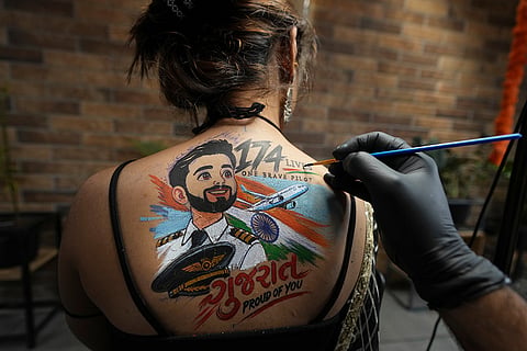 An Indian woman gets a temporary tattoo, depicting Indian FlyDubai pilot Smit Machchhar, on her back ahead of Navratri, a nine night Hindu festival, in Ahmedabad, India, Thursday, Oct. 8, 2026.