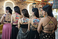 | Photo: AP/Ajit Solanki : Indian women pose for photographs as they show temporary tattoos on their back ahead of Navratri, a nine night Hindu festival, in Ahmedabad, India, Thursday, Oct. 8, 2026.