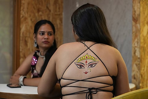 An Indian woman with a temporary tattoo on her back talks with another ahead of Navratri, a nine night Hindu festival, in Ahmedabad, India, Thursday, Oct. 8, 2026.