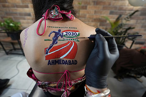 An Indian woman gets a temporary tattoo depicting, upcoming commonwealth games to be held in Ahmedabad, on her back ahead of Navratri, a nine night Hindu festival, in Ahmedabad, India, Thursday, Oct. 8, 2026.