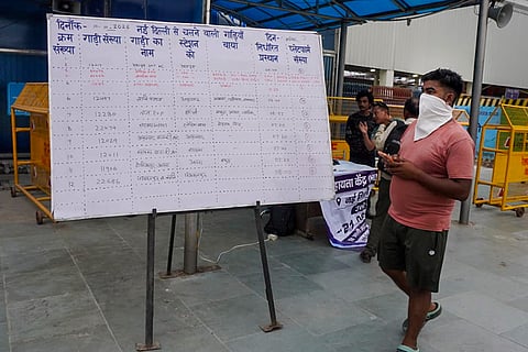 Passengers walk past a notice board outside the New Delhi Railway Station amid heightened security arrangements following planned protests by Cockroach Janta Party (CJP) members, in New Delhi.