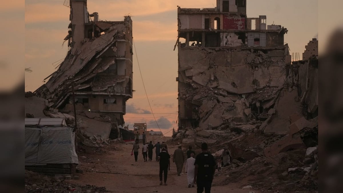Palestinians walk along a street surrounded by buildings destroyed in Israeli military strikes during the Israel-Hamas war in Gaza City - AP Photo/Jehad Alshrafi