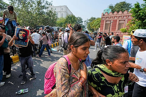 Protesters take cover as police arrives to detain them during a demonstration demanding the resignation of Chief Election Commissioner Gyanesh Kumar in New Delhi, India, Saturday, Oct. 10, 2026.