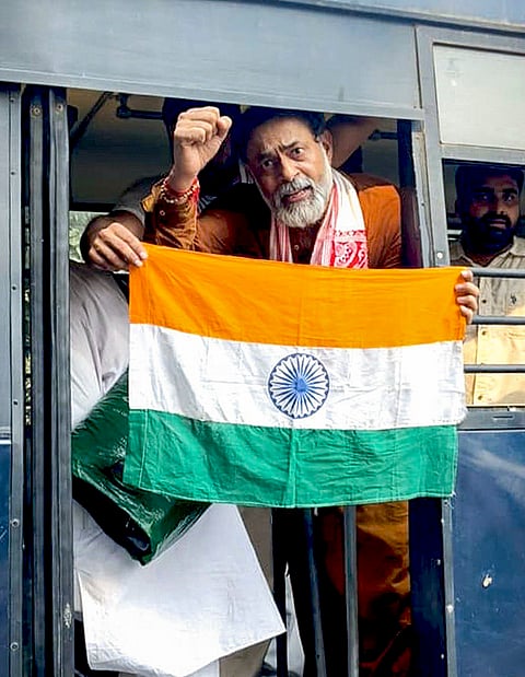 Activist Yogendra Yadav holds the national flag from inside a police vehicle after being detained during a demonstration by the Cockroach Janta Party (CJP) demanding the resignation of Chief Election Commissioner (CEC) Gyanesh Kumar over alleged electoral roll irregularities, in New Delhi. 
