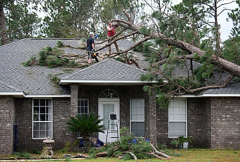 Jeff Lundy cuts up a pine tree that fell on his father-in-law's house during Isaias on Saturday, Oct. 10, 2026, in Milton, Florida. 
