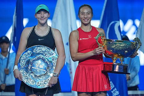 Zheng Qinwen, of China, left, holds winners trophy as Mirra Andreeva, of Russia, holds the runner's-up trophy as they pose for photos after their women's singles final match at the China Open tennis tournament in Beijing, Sunday, Oct. 11, 2026.