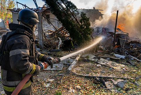 A rescue worker puts out a fire at residential houses destroyed in a Russian strike on Kharkiv, Ukraine, Sunday, Oct. 11, 2026. 