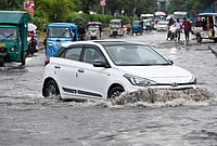 | Photo: PTI  : Commuters make their way through a waterlogged road after heavy rain, in Noida.