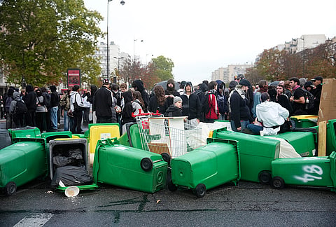 Students stand in front of the Helene Boucher high school blockaded with garbage bins as they protest against under-resourced schools in Paris, Tuesday, Oct. 13, 2026. 