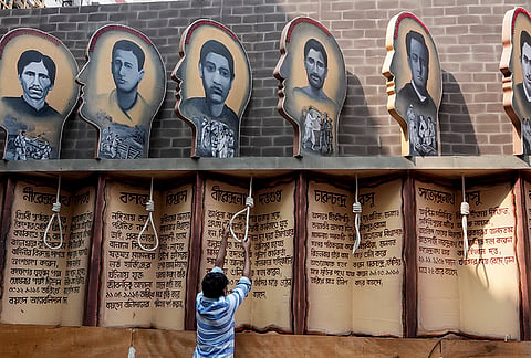 A worker adjusts execution noose props beneath portraits and biographical panels honoring Indian freedom fighters at a community Durga Puja pandal, in Kolkata, West Bengal, Friday, Oct. 9, 2026. 