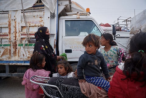 Children gather around a motorcycle as displaced families prepare to leave al-Talayi camp in Hassakeh, Syria, Tuesday, Oct. 13, 2026. 