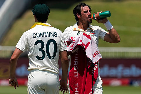 Australia's Mitchell Starc, right, takes refreshments at the end of his over on day five of the first cricket test match between South Africa and Australia, in Durban, South Africa, Tuesday, Oct. 13, 2026.
