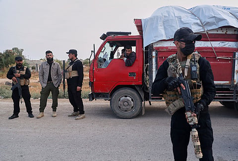 Internal security forces guard displaced families returning to the Ras al-Ayn countryside after seven years of displacement during a stop en route from Hassakeh, Syria, Tuesday, Oct. 13, 2026. 
