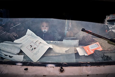 A young child looks through a truck's windshield as displaced families prepare to leave al-Talayi camp in Hassakeh, Syria, Tuesday, Oct. 13, 2026. 
