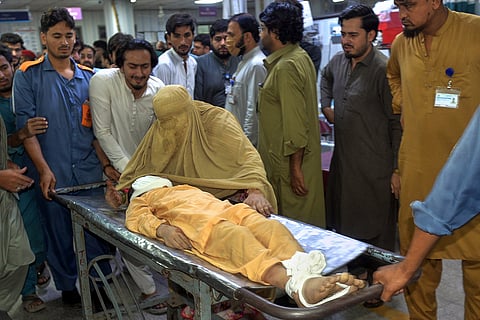 A woman mourns next to the body of a boy, who was killed in the roof collapse of a private school, at a hospital in Peshawar,  Pakistan, Thursday, Oct. 15, 2026.