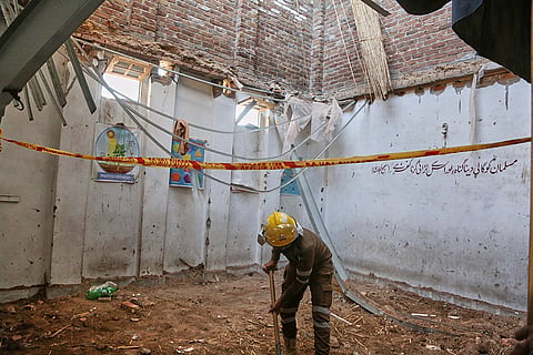 A rescue worker searches through the rubble of a roof collapse at a private school, in Peshawar, Pakistan, Thursday, Oct. 15, 2026.