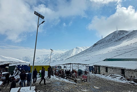 Security personnel and tourists at a pit stop on Mughal Road covered in fresh snow, in Shopian district, Jammu and Kashmir, Thursday, Oct. 15, 2026. 