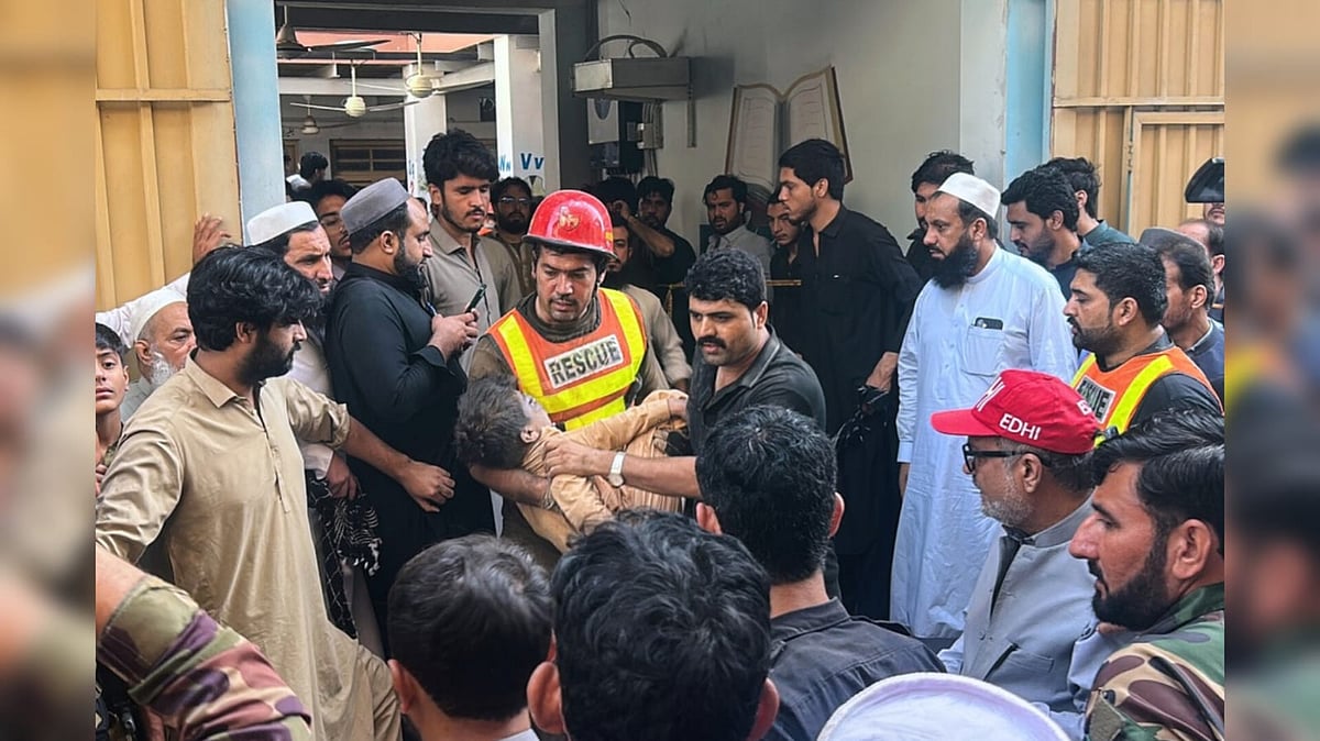 A rescue worker carries an injured child after rescuing him from the rubble of a roof collapse at a private school, in Peshawar - AP Photo/Arif Khan