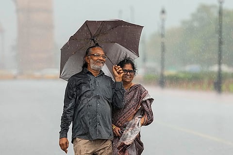 People take a walk on the Kartavya Path during heavy rainfall, near the India Gate, in New Delhi, Thursday, Oct. 15, 2026. 