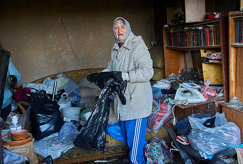 An elderly woman cleans up the mess in her damaged apartment after a missile strike during Russia's night air attack in Kyiv, Ukraine, Wednesday, Oct. 14, 2026. 