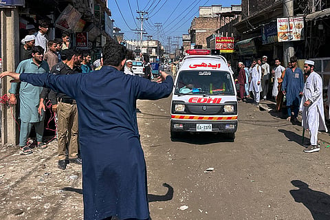 A volunteer clears the way for an ambulance transporting injured school children following a roof collapse at a private school in Peshawar, Pakistan, Thursday, Oct. 15, 2026.
