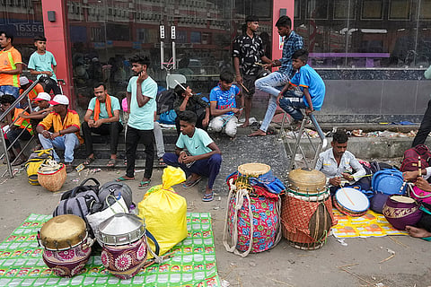 Dhakis, traditional Bengali drummers, wait at Sealdah railway station after arriving from rural areas, hoping to be hired by Durga Puja committees for the remaining four days of the festival, in Kolkata, West Bengal, Thursday, Oct. 15, 2026. 