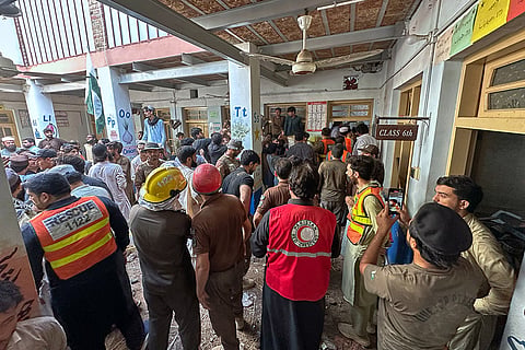 Rescue workers and volunteers take part in the rescue operation at the site of a roof collapse at a private school, in Peshawar, Pakistan, Thursday, Oct. 15, 2026.