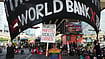 | Photo: AP/Sakchai Lalit : Protesters hold banners during a demonstration near the venue of meetings of the International Monetary Fund and the World Bank Group in Bangkok, Thailand, Thursday, Oct. 15, 2026. 