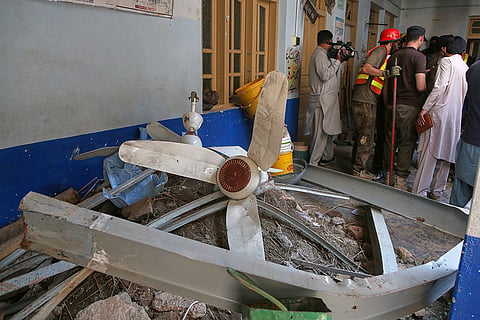 Rescue workers take a break while searching through the rubble at the site of a roof collapse at a private school, in Peshawar,  Pakistan, Thursday, Oct. 15, 2026.