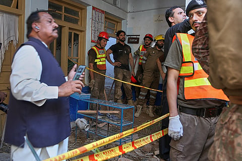 Rescue workers take break while searching through the rubble of a roof collapse at a private school, in Peshawar, Pakistan, Thursday, Oct. 15, 2026.